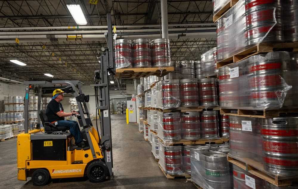 Photo of an operator driving a forktruck, stacking pallets of kegs